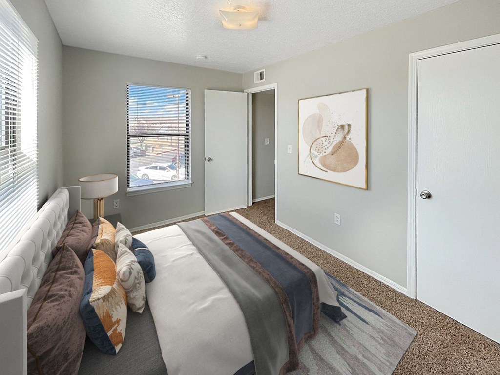 A bedroom with a bed, a window, and a painting on the wall.
